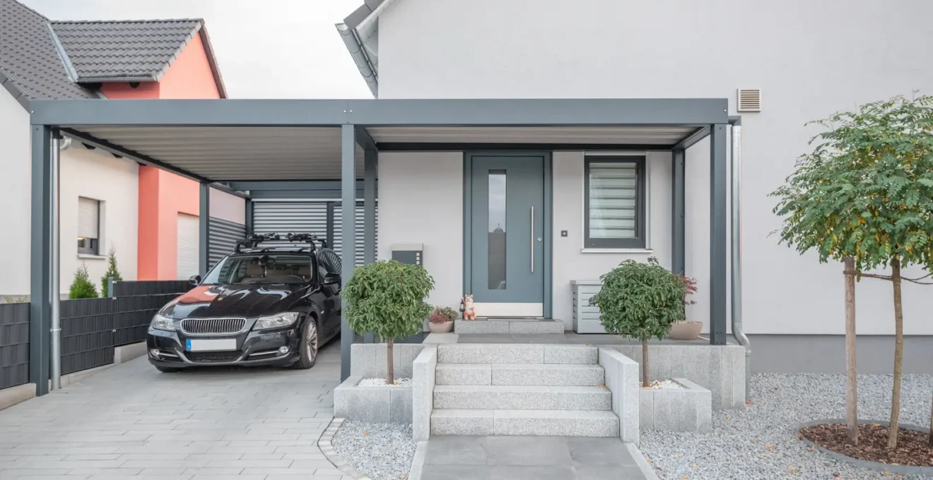Un homme mesure la hauteur disponible sous un carport près d'une moto stationnée.